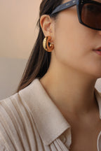 Gold chunky hoop earrings with a glossy finish, designed as bold statement pieces for stylish accessorizing.