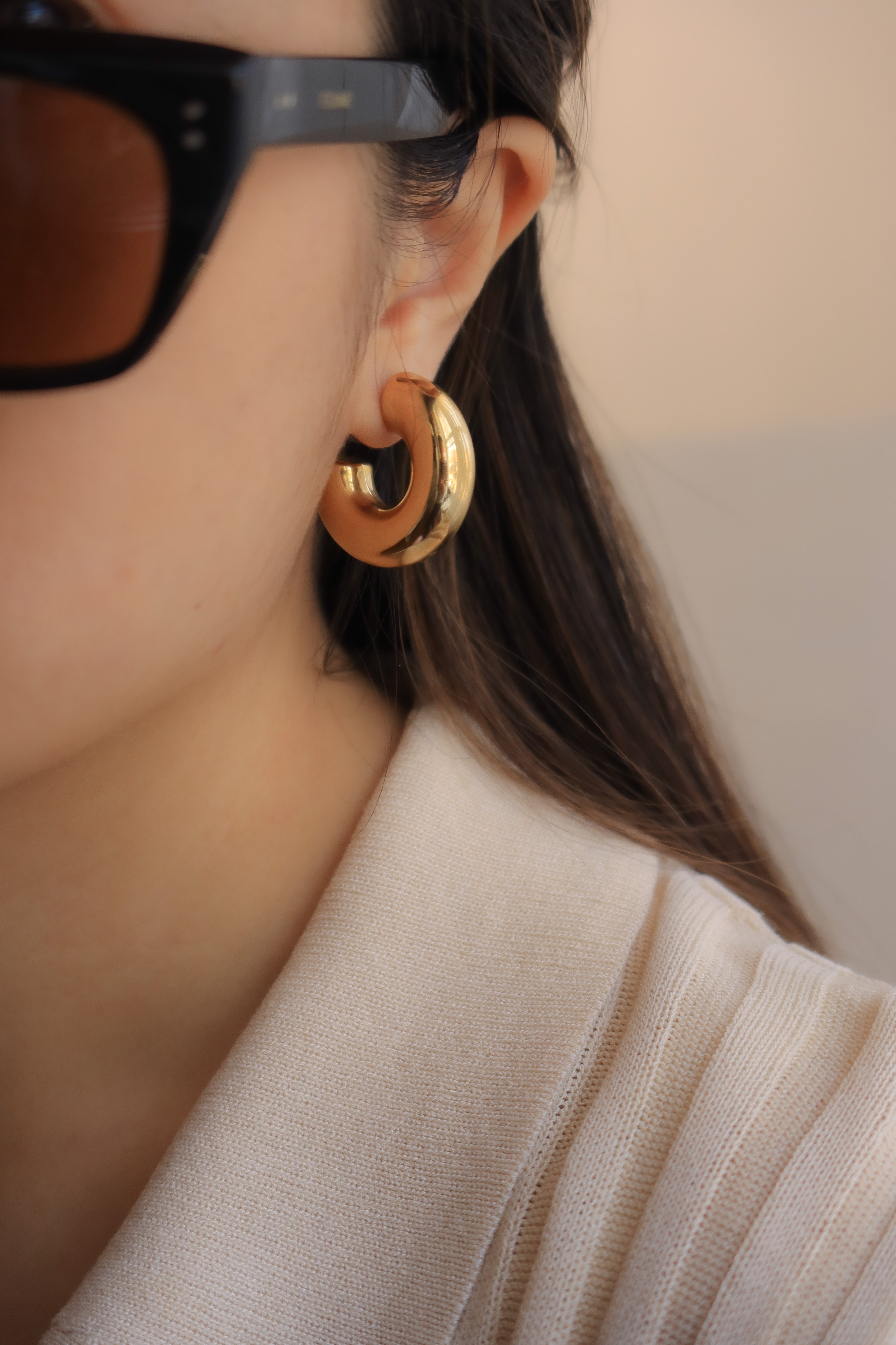 Gold chunky hoop earrings with a glossy finish, designed as bold statement pieces for stylish accessorizing.