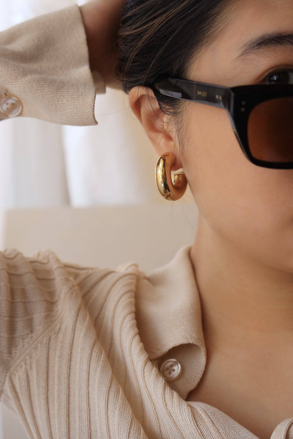 Gold chunky hoop earrings with a glossy finish, designed as bold statement pieces for stylish accessorizing.