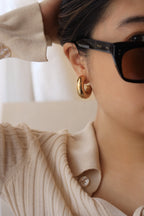 Gold chunky hoop earrings with a glossy finish, designed as bold statement pieces for stylish accessorizing.