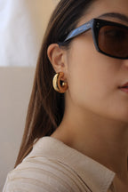 Gold chunky hoop earrings with a glossy finish, designed as bold statement pieces for stylish accessorizing.