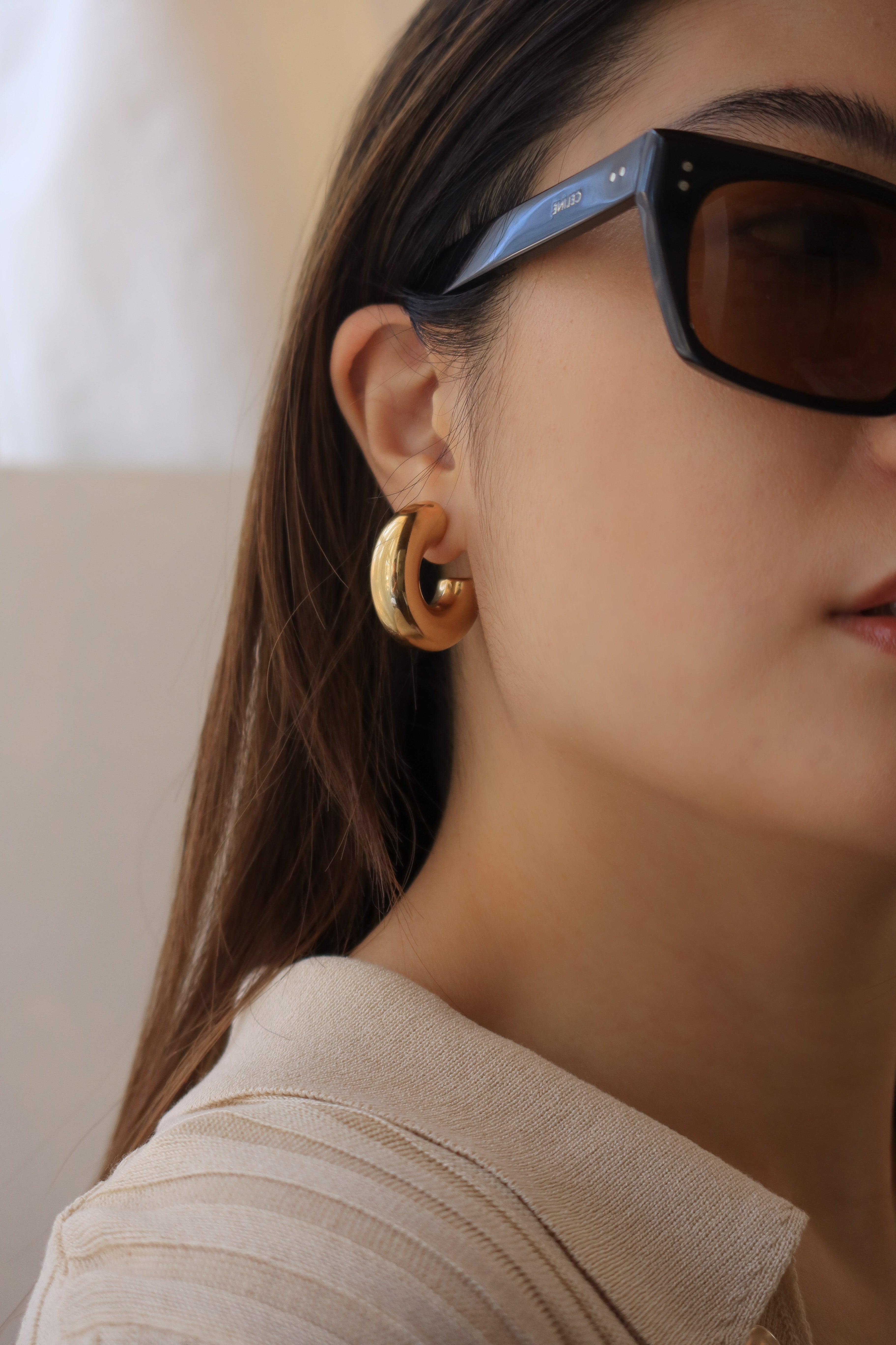 Gold chunky hoop earrings with a glossy finish, designed as bold statement pieces for stylish accessorizing.