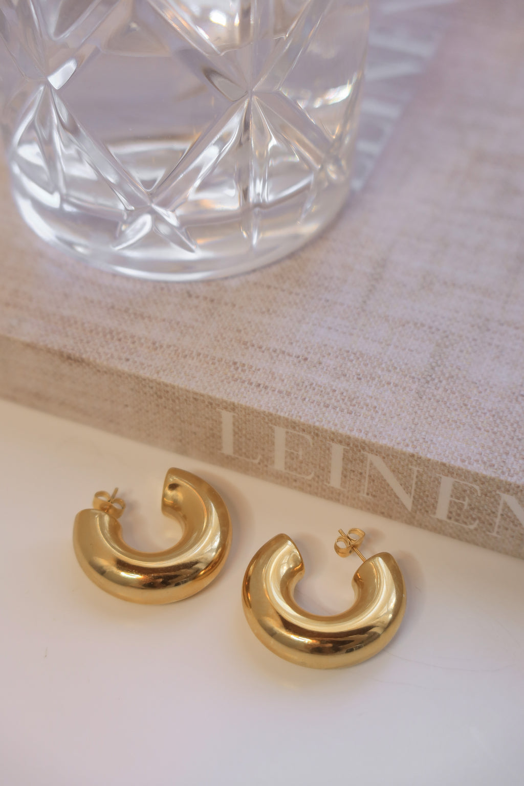 Gold chunky hoop earrings with a glossy finish, designed as bold statement pieces for stylish accessorizing.