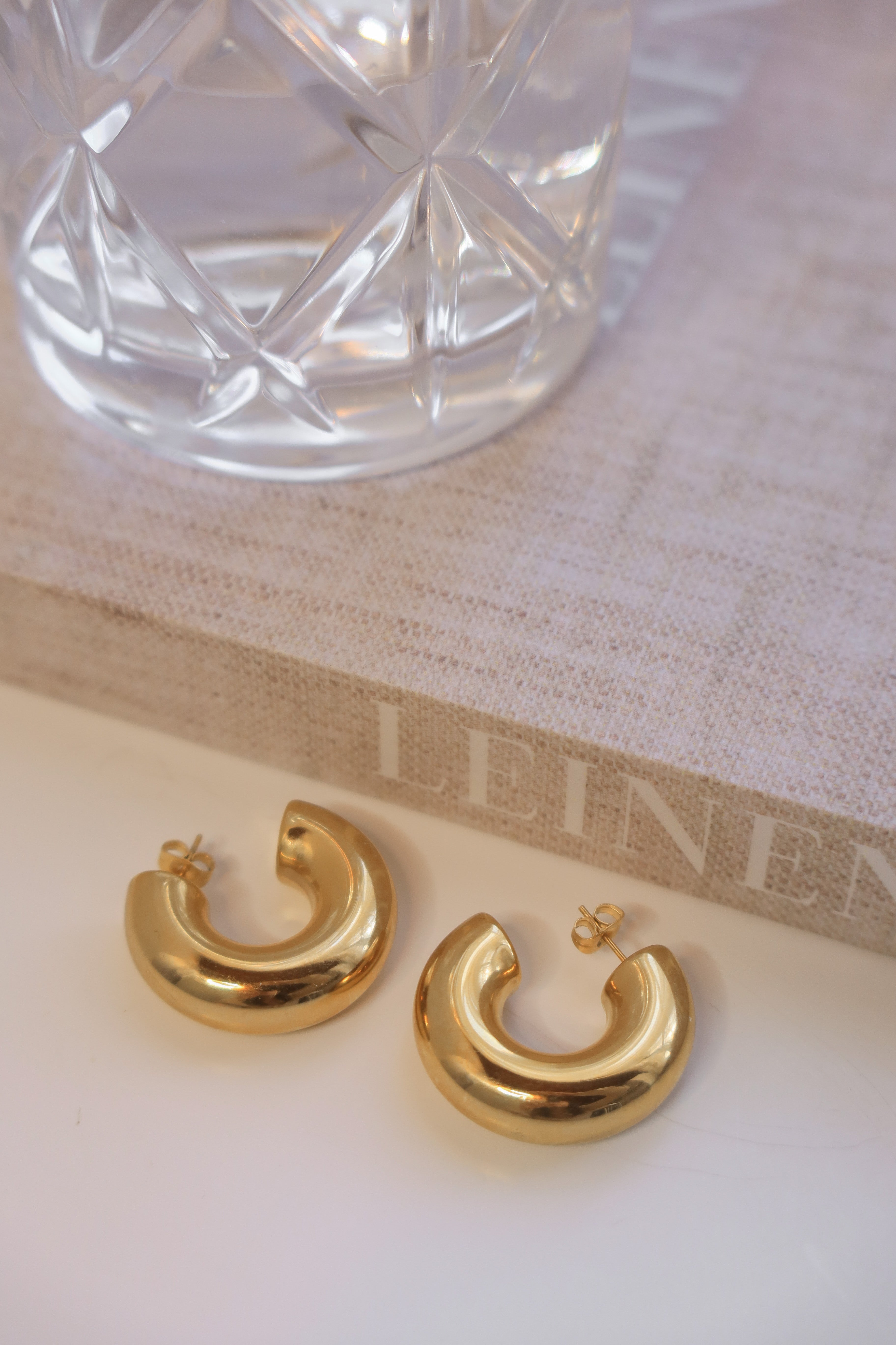 Gold chunky hoop earrings with a glossy finish, designed as bold statement pieces for stylish accessorizing.