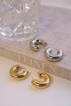 Assortment of chunky hoop earrings in gold and silver with a glossy finish, showcasing bold, statement designs suitable for fashion-forward styling