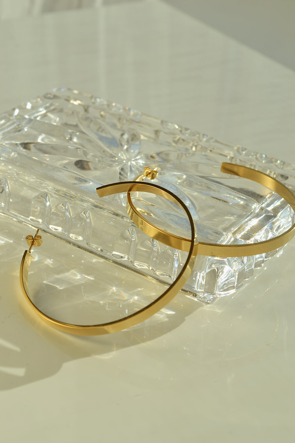 Large glossy gold hoop earrings with a smooth, shiny finish, reflecting light elegantly.