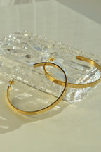 Large glossy gold hoop earrings with a smooth, shiny finish, reflecting light elegantly.