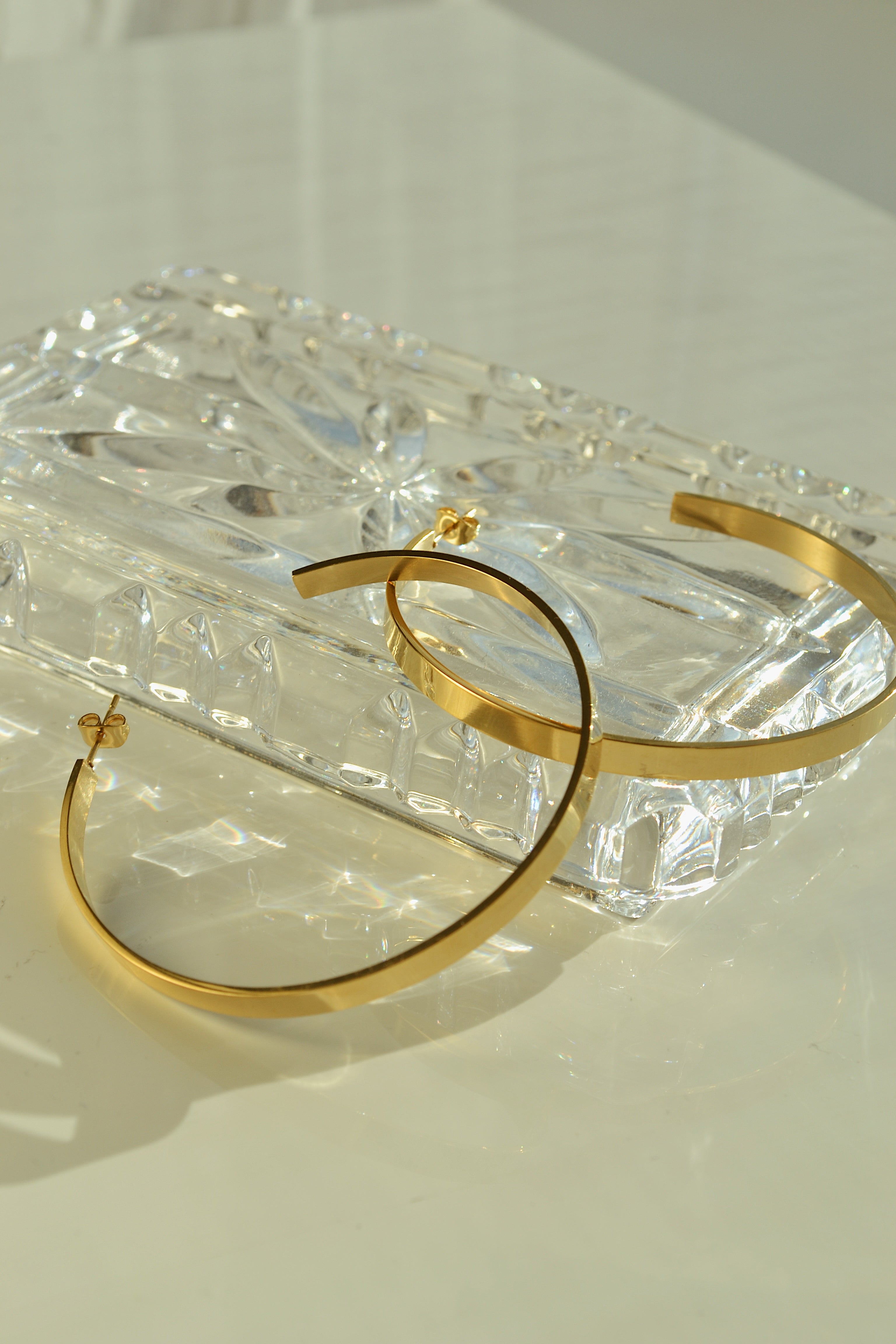 Large glossy gold hoop earrings with a smooth, shiny finish, reflecting light elegantly.