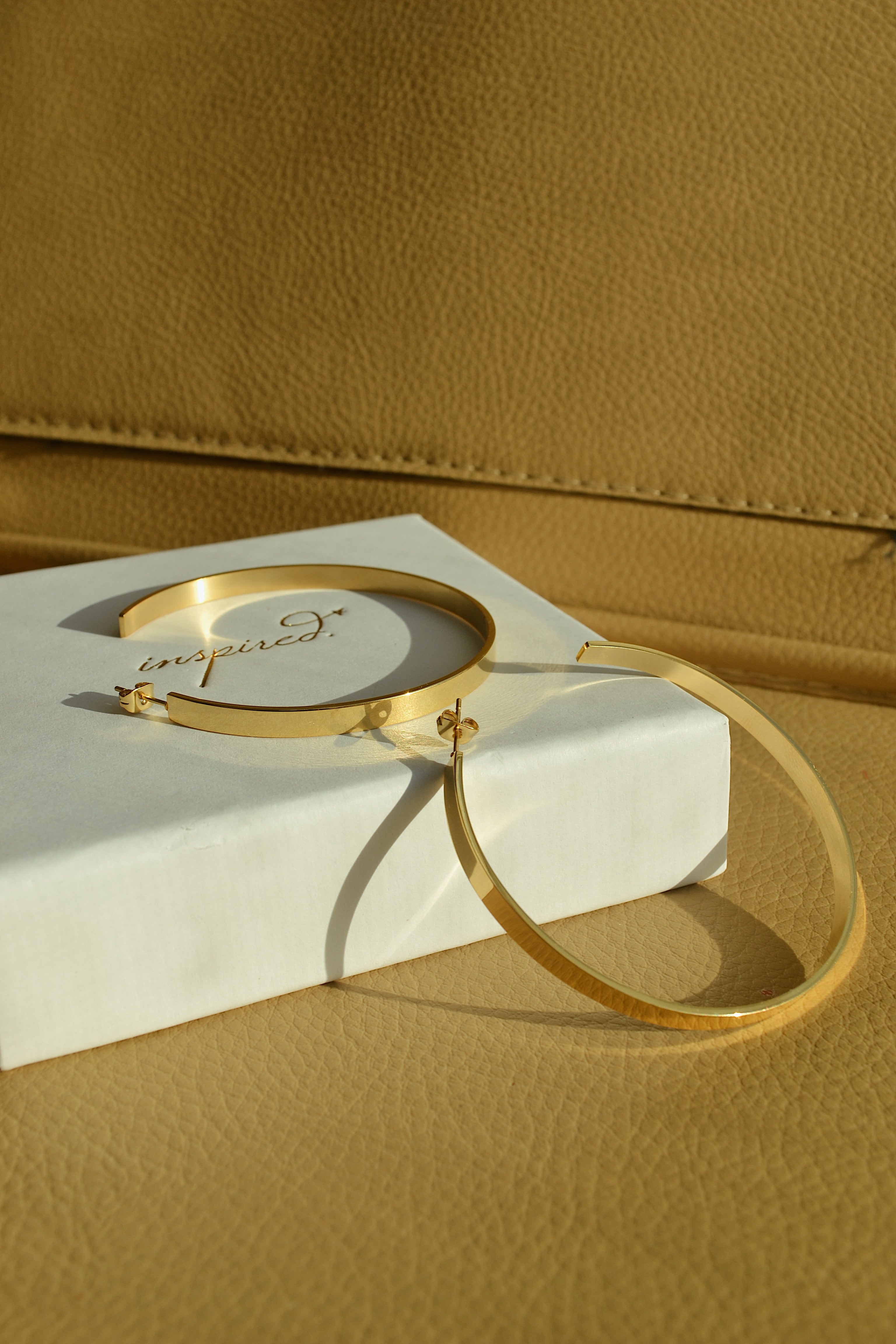 Large glossy gold hoop earrings with a smooth, shiny finish, reflecting light elegantly.