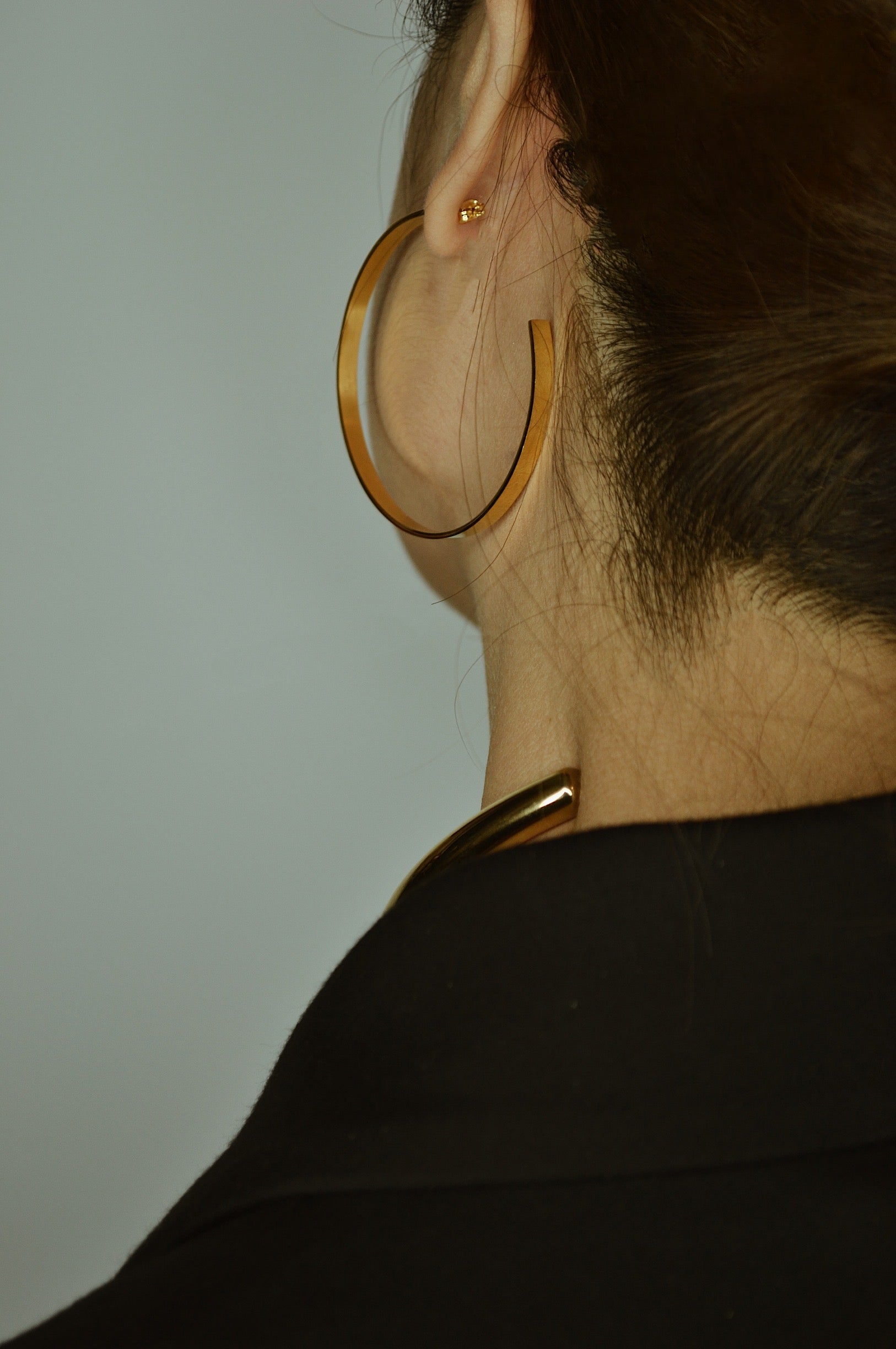 Large glossy gold hoop earrings with a smooth, shiny finish, reflecting light elegantly.