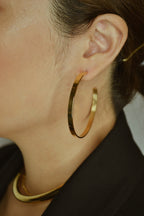Large glossy gold hoop earrings with a smooth, shiny finish, reflecting light elegantly.