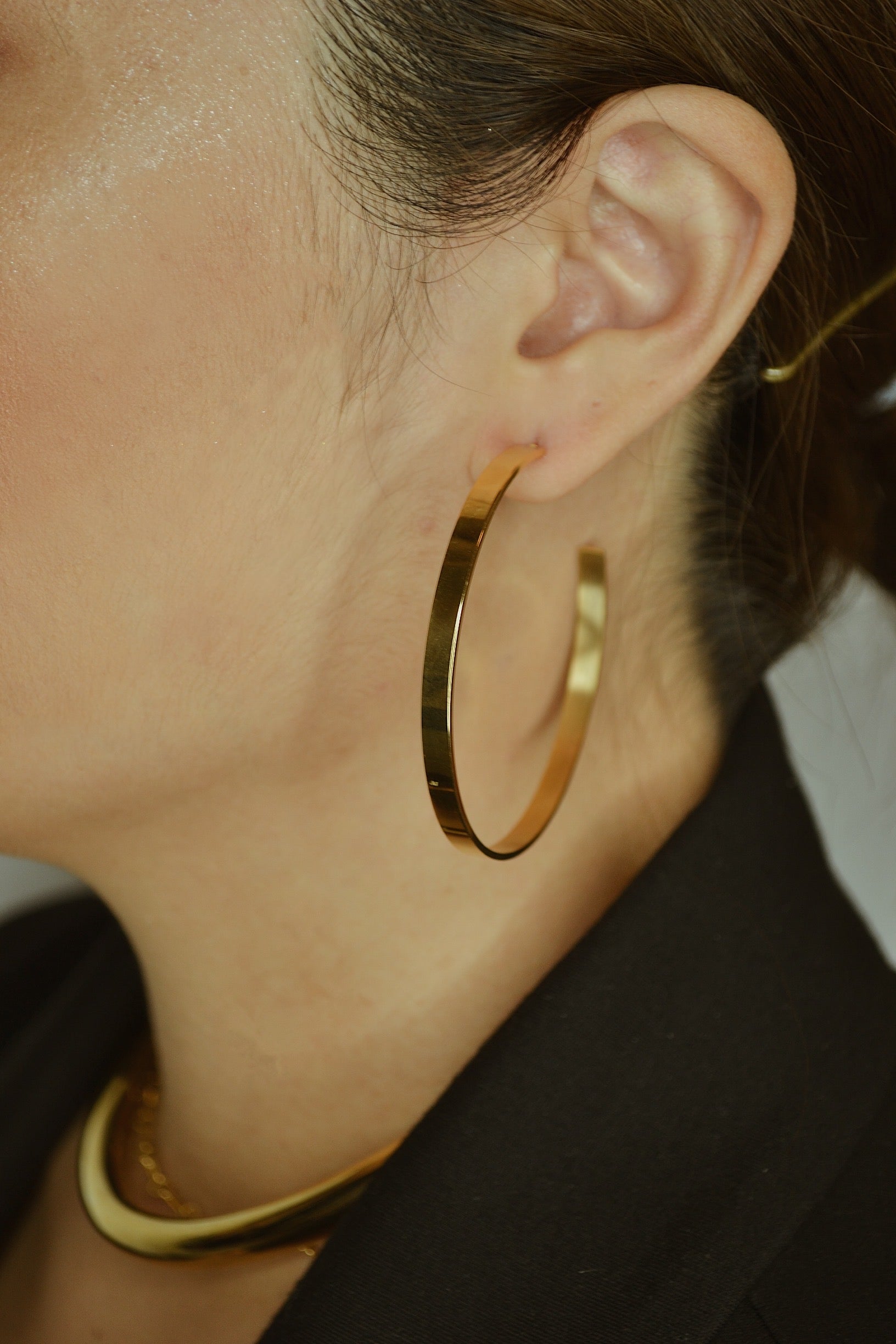 Large glossy gold hoop earrings with a smooth, shiny finish, reflecting light elegantly.