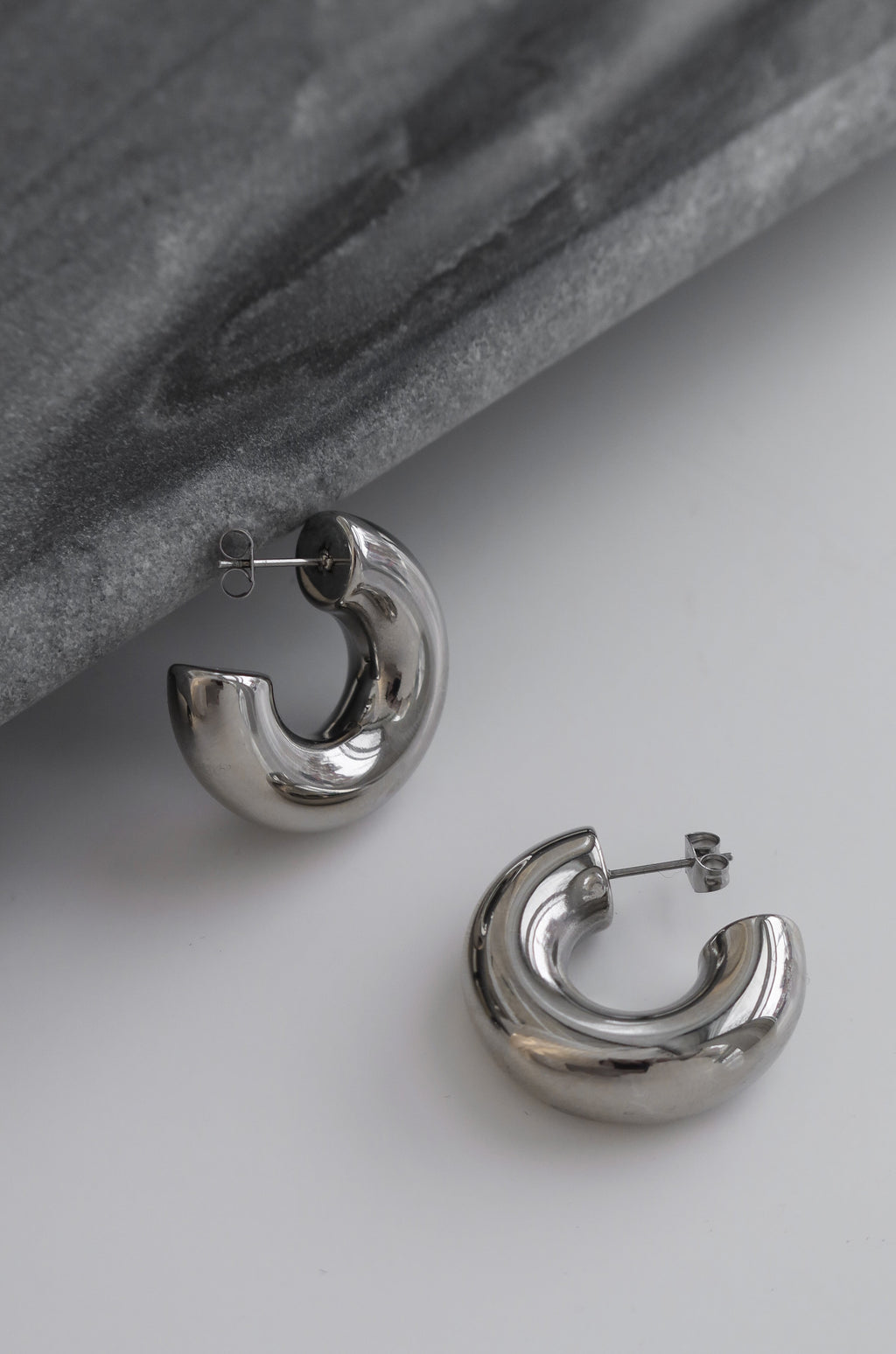 Silver chunky hoop earrings with a glossy finish, designed as bold statement accessories