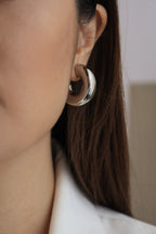 Silver chunky hoop earrings with a glossy finish, designed as bold statement accessories