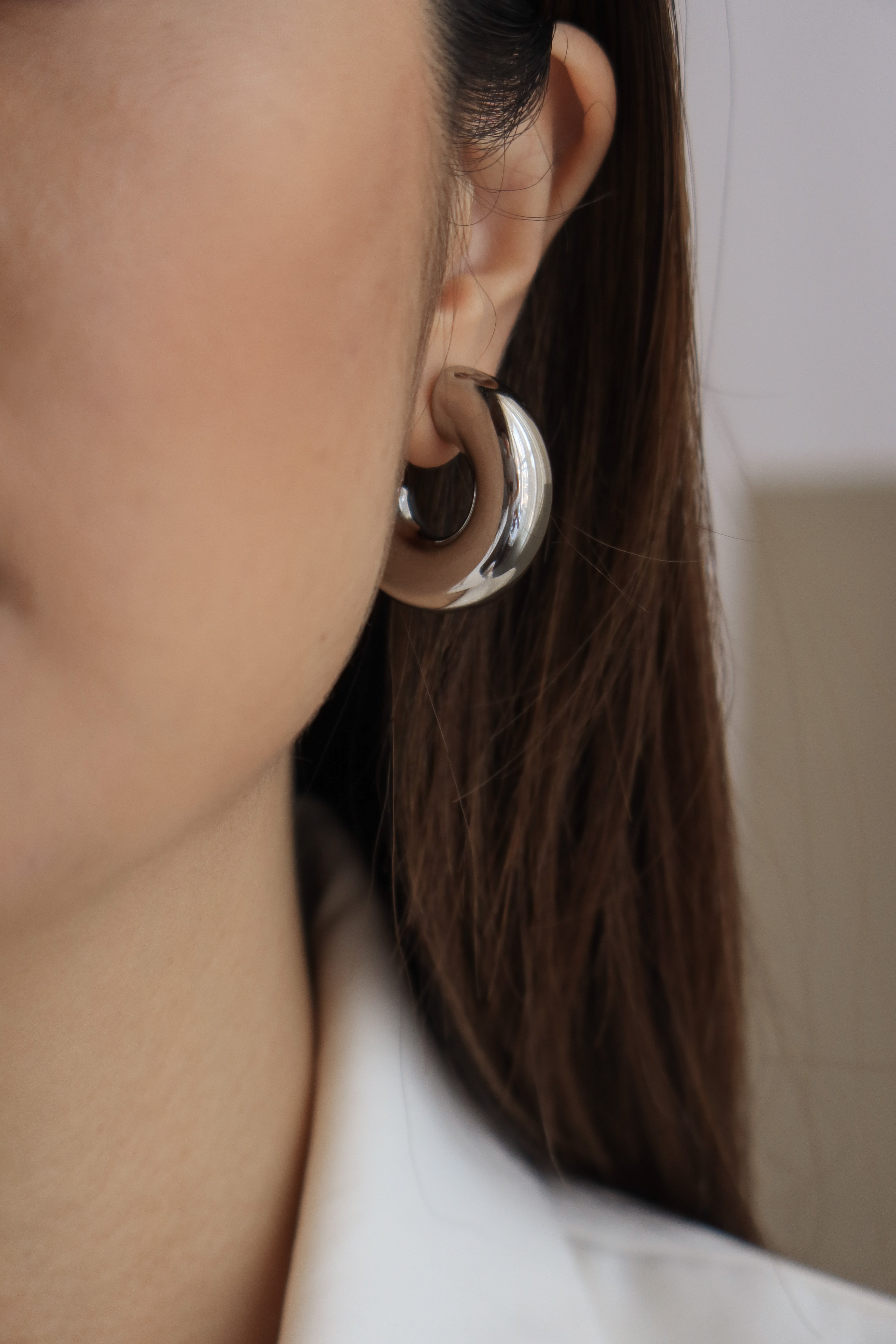 Silver chunky hoop earrings with a glossy finish, designed as bold statement accessories